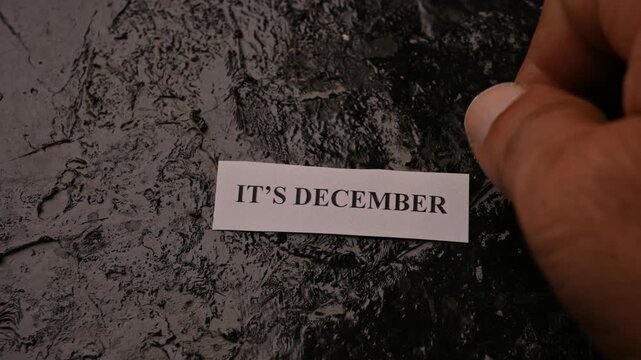 It's December Text on Tiny Paper Placed on Black Book Background