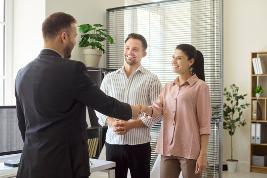 Clients couple handshake with realtor in office. Friendly meeting with an agent on agreement, consultation and contract for property purchase in a modern workspace. Concept of trust and deal.