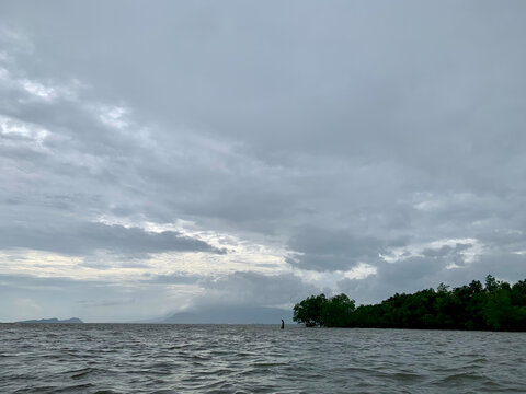 Distant silhouette of a person walking in shallow sea with Bokor Mountain in Kep, Cambodia