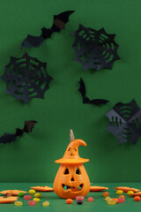 Obraz premium Halloween celebration concept with jack-o'-lantern bucket candy and paper bats on green background