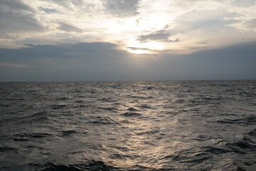 Obraz premium Golden Sunlight Over a Calm Ocean Horizon Beneath Dramatic Clouds