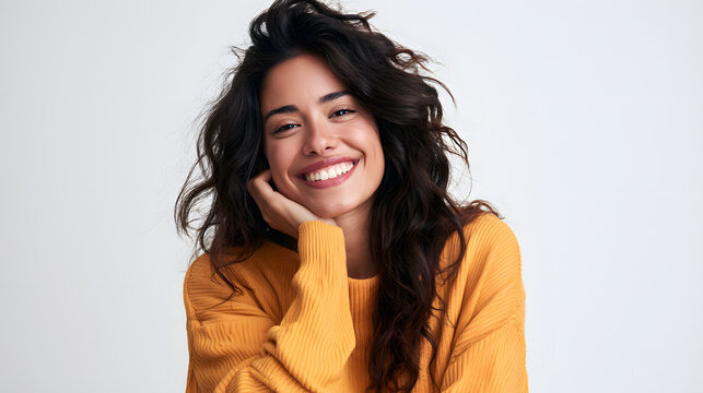 A young Hispanic woman with a smiling and attractive appearance is posing for a studio shot