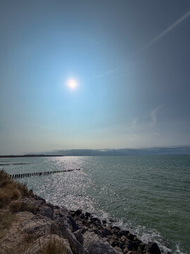 Sunlight sparkling over the sea with wooden breakwaters and rocky shore in Wissant, France
