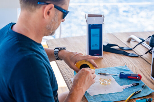 Man repairing yacht equipment with hand tools during a sailing trip on the Adriatic Sea. Concept of boat maintenance, DIY repair, seamanship, technical skills and self-sufficient sailing.