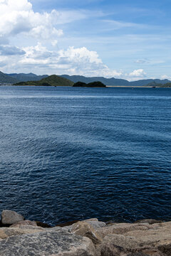 View of calm water and distant islands under blue sky in coastal area