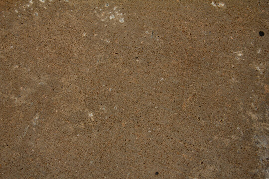 Concrete surface shows texture with small dots and lines in an outdoor setting during daylight hours