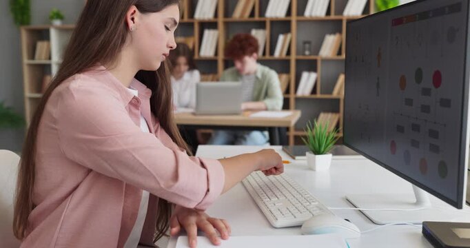 Teenager student girl reviews data charts on computer. In a classroom she advances a school project and deepens research with clear analysis for learning. Strong concept of digital education.