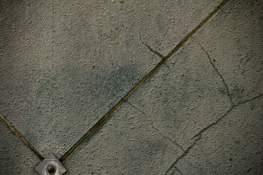 Concrete surface with crack lines and metal fixture visible