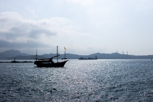 Boat sails on the water with mountains in the background during cloudy day