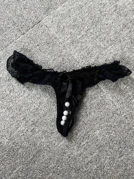 Black Lace Thong Underwear with Pearl Detail Flat Lay on Gray Fabric Fashion Product
