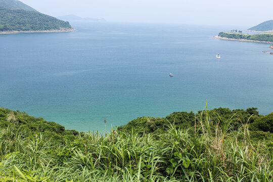 View of calm water and hills in the distance near coastal area with boats in the morning