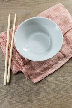 Bowl and chopsticks on a pink cloth on a wooden table