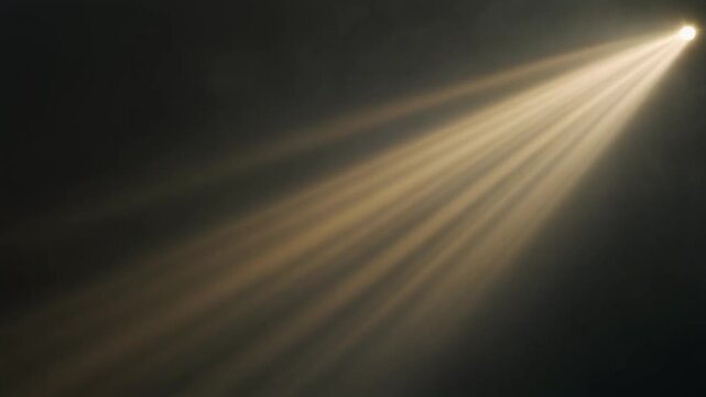 Volumetric golden light rays rotate slowly through atmospheric mist, sweeping diagonally across deep charcoal darkness with cinematic contrast, dramatic haze and generous copy space.