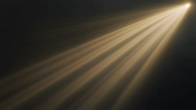 Volumetric golden light rays rotate slowly through atmospheric mist, sweeping diagonally across deep charcoal darkness with cinematic contrast, dramatic haze and generous copy space.