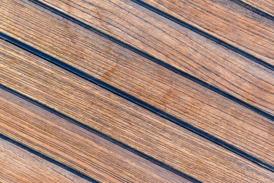 Close up of teak wooden decking on a sailing yacht creating a clean nautical texture and seamless background. Concept of marine design, luxury boating, craftsmanship and premium natural materials.
