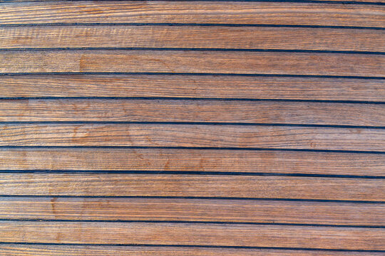 Close up of teak wooden decking on a sailing yacht creating a clean nautical texture and seamless background. Concept of marine design, luxury boating, craftsmanship and premium natural materials.