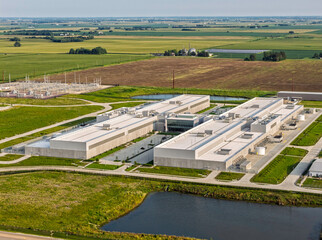 Fototapeta premium Aerial view of huge data center facility with rooftop cooling units and surrounding industrial infrastructure in DeKalb, Illinois