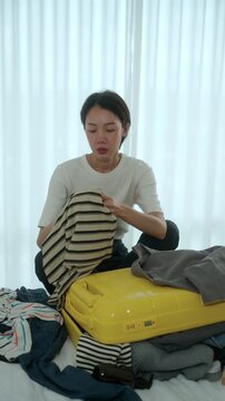 Stressed young woman struggling to pack an overfilled suitcase before a trip at home. Travel preparation luggage organization, packing stress. Vacation planning and travel anxiety concept.
