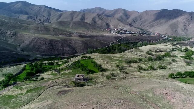 Professional drone shot reveals fire temple ruins from distance with dramatic mountainous background and green patches around.