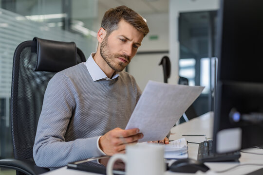 Happy smiling employee, young entrepreneur using digital tablet computer analyzing finance trading market data working standing in open space office