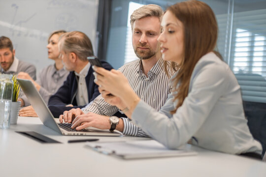 Successful businesspeople working in a coworking space working with laptop discussing strategy and business plan in modern office.