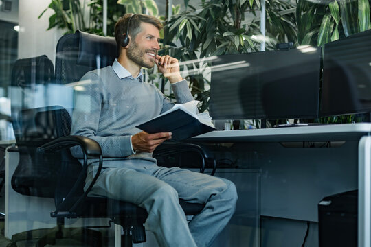 Happy call center agent wearing headset talking to client working in customer support office