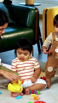 Indian Asian twin infant babies playing with colorful toys while young father and mother sit together on carpet in modern living room at home, capturing joyful family bonding and parenthood moments
