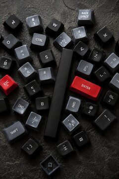 Computer keyboard keys scattered on dark surface with red Enter and Esc keys, technology and typing concept