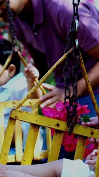 Indian Asian young parents gently swinging twin infant babies on playground swing in outdoor park, smiling as babies laugh and enjoy fresh air, nature greenery and joyful family bonding time together