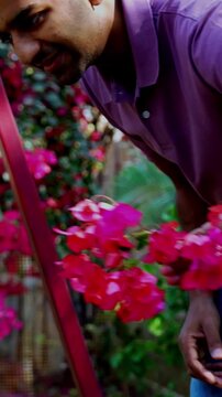 Indian Asian young parents gently swinging twin infant babies on playground swing in outdoor park, smiling as babies laugh and enjoy fresh air, nature greenery and joyful family bonding time together