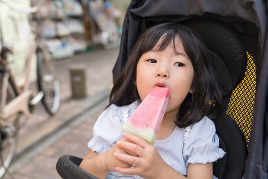 ベビーカーに座りスイカを頬張る日本人の女の子の幼児
