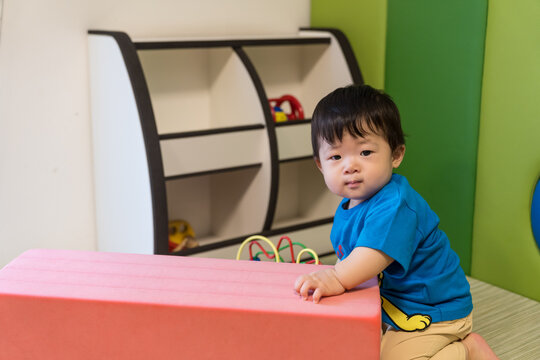 キッズルームのピンクのソフトブロックにもたれている日本人の男の赤ちゃん