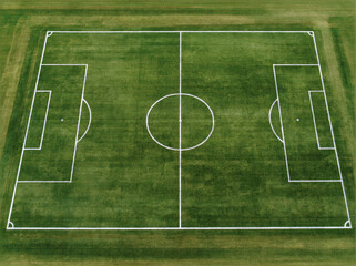 Naklejka premium Soccer field with white line marking on green grass, aerial view of empty sport pitch