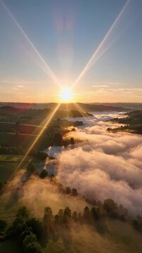 Sunrise Over Foggy Valley and Rolling Hills Aerial View - A breathtaking aerial view captures the sunrise illuminating a valley filled with soft fog, casting long shadows across the rolling, green