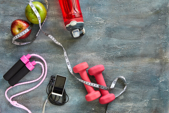 Attributes of a healthy lifestyle. Fruits, dumbbells, a bottle of water, rope, meter, player on a blue background with stains. Diet plan. View from above. Sport and healthy mode. Copy space.