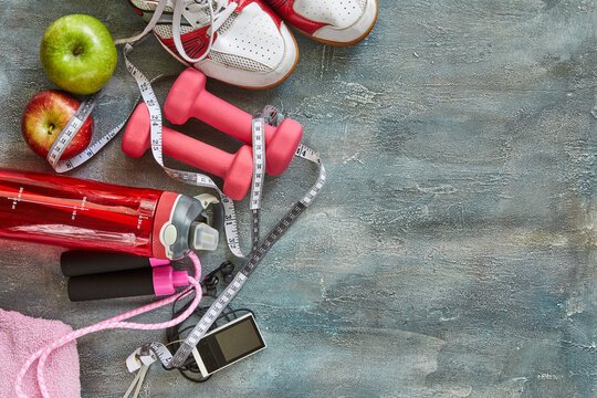 Attributes of a healthy lifestyle. Fruits, dumbbells, a bottle of water, rope, sneakers and a meter on a blue with divorce background. Calorie counting. Diet plan. View from above. Close-up.