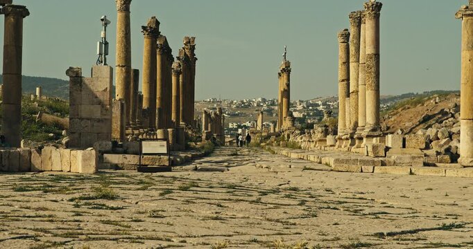 Wide view of the ancient Roman Cardo Maximus with towering stone columns at the archaeological site of Jerash, Jordan, under warm daylight with a timeless historical atmosphere