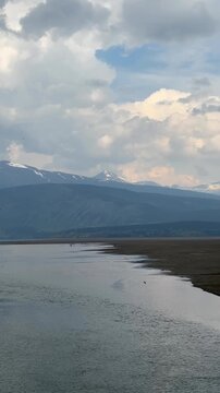 Panoramic view capturing Carcross beach, Bennett Lake, and surrounding mountains under cloudy sky in Yukon, Canada