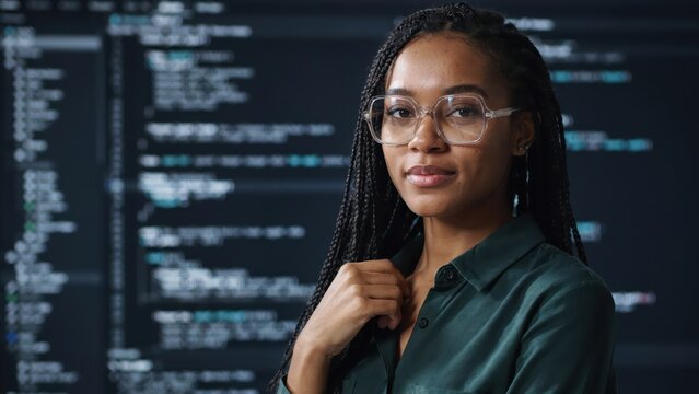 Professional female software developer wearing clear glasses and green shirt poses confidently for digital portrait photo