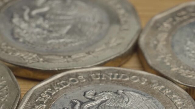 Close up of Mexican peso coins featuring the national coat of arms with the eagle and serpent, highlighting engraved metal texture and monetary details