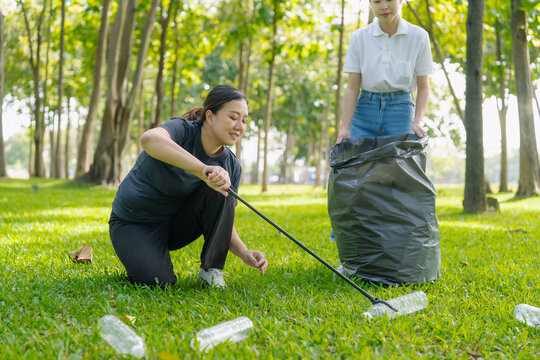 Asian Women Volunteers Collecting Plastic Bottle Garbage into Trash Bag in Green Park for Environmental Protection and Recycling Concept