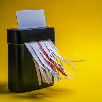 Paper Shredder Destroying Documents on Yellow Background with Copy Space