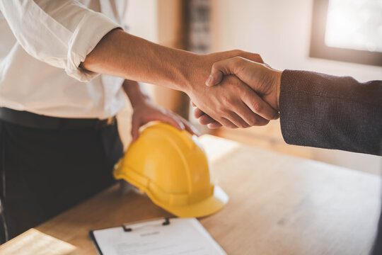Successful deal, male architect shaking hands with client in construction site after confirm blueprint for renovate building