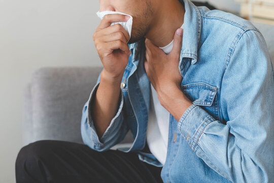 Sick day at home. Asian man has cough and common cold at home.