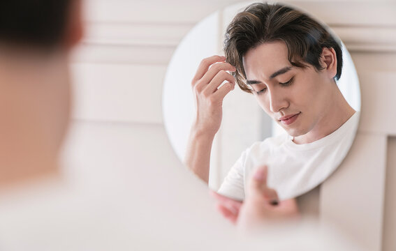 Closeup portrait of handsome beautiful asian boy mirror makeup routine with copy space. Beauty influencer guy with perfect glow skin dress up. Healthcare man lifestyle cosmetic blogger hair concept