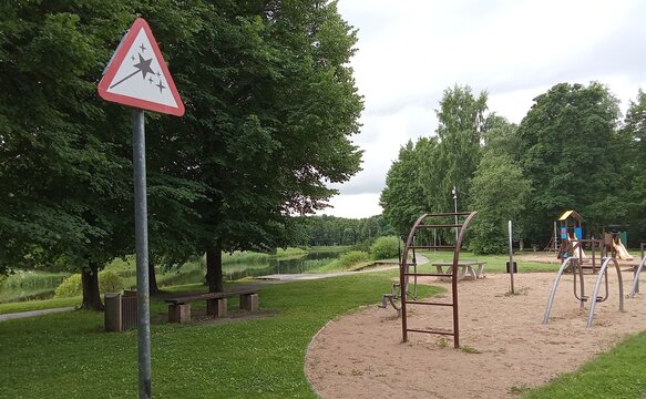 Red Triangular Playground Fun Symbol and Outdoor Recreation Area in Green Public Park.

