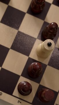 Hand maneuvers wooden pawn across checkered board to challenge dark pieces while planning final victory in silent home setting during soft light of dusk as focused player executes clever tactical play