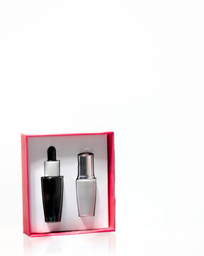 Luxury beauty gift set with black serum bottle and silver pump dispenser in a pink-lined box on a glass shelf. Ideal for cosmetic marketing and advertising, sales