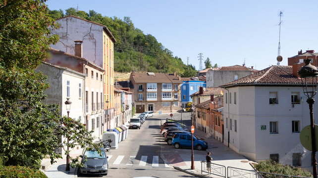 Calle de ciudad con coche edificio fachada &aacute;rbol y colina verde bajo cielo azul en Burgos, Espa&ntilde;a