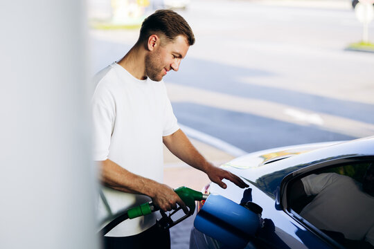 Man filling up car with a pump nozzle at a gas station, refueling for travel and transportation